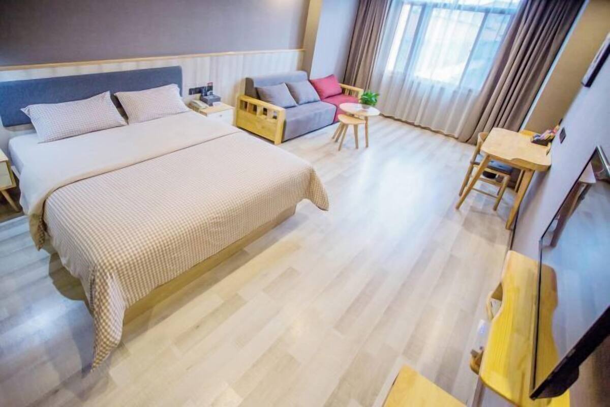 Hotellihuone, jossa on suuri sänky, sohva, pieni pöytä ja työpöytä.