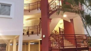 Un edificio a più piani con una scala centrale, balconi e una palma.