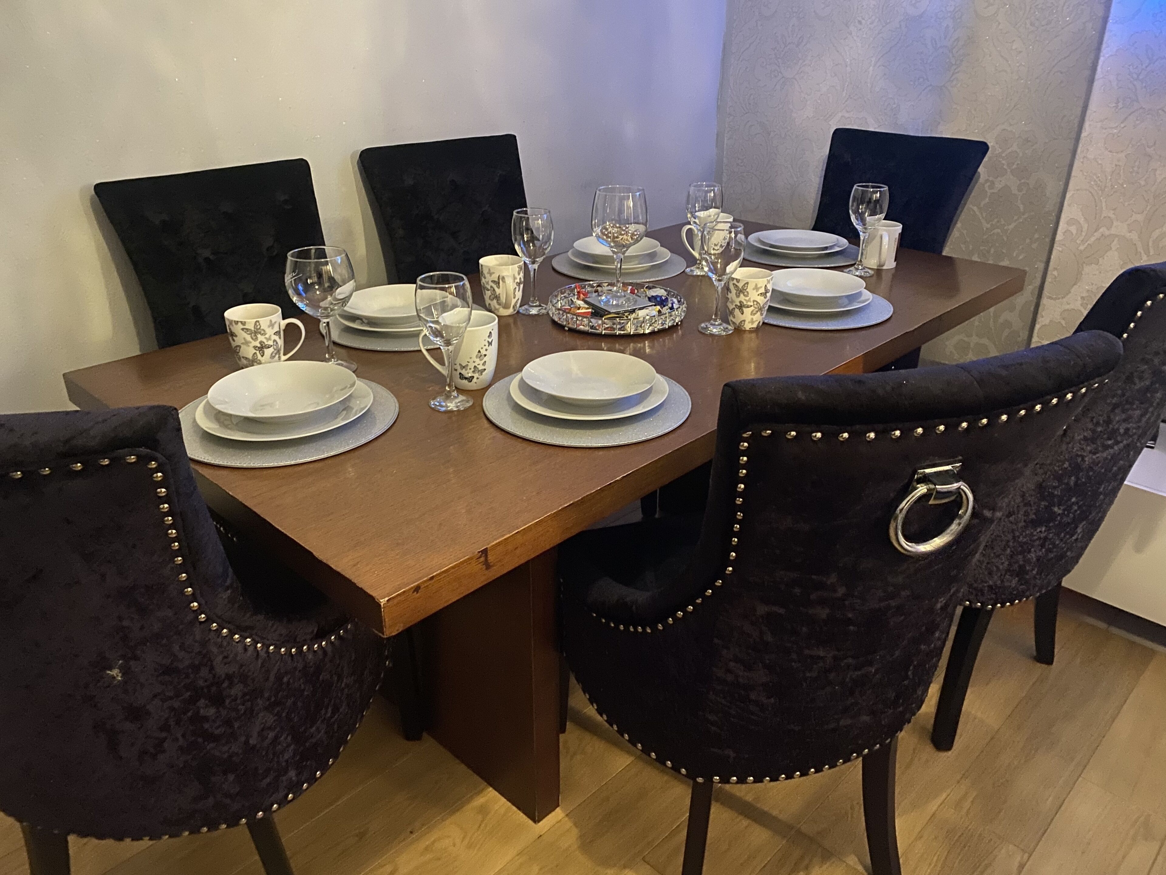 Una mesa de comedor preparada con platos, vasos y un centro de mesa decorativo.