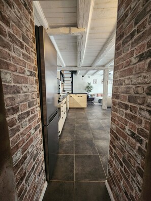 Una cocina con refrigerador, armarios de madera y piso de baldosas.