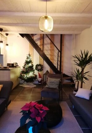 A living room with a staircase, a Christmas tree, and a coffee table with a plant.