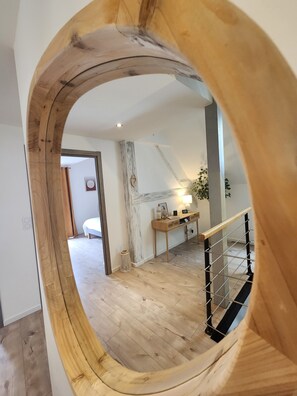 Una habitación con piso de madera, un escritorio con lámpara y una escalera con barandilla.