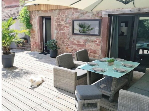 A patio with wicker furniture, a table set for dining, and potted plants.