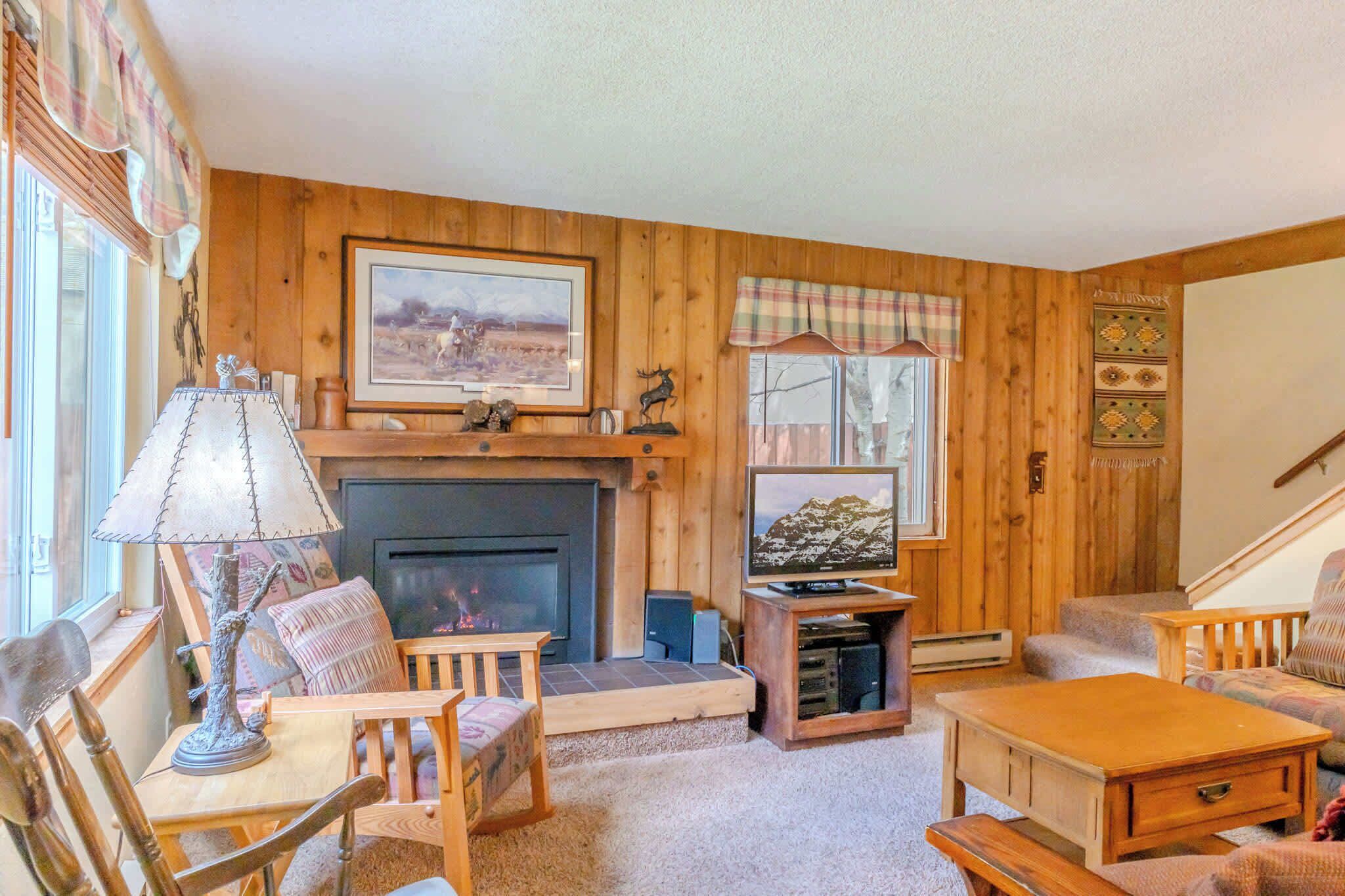 A cozy living room with a fireplace, wooden furniture, and a television.