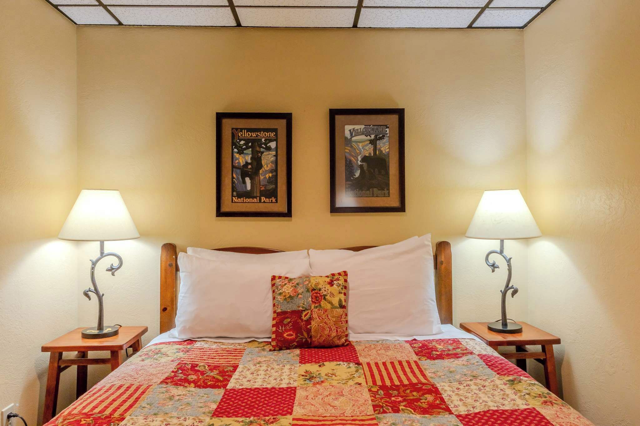 A bed with a quilt, two framed posters, and two bedside lamps.