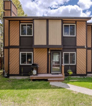 A modern multi-story building with a flat roof, large windows, and a front porch with a grill. - Lodgepole Condo Unit 5 (West Yellowstone)
