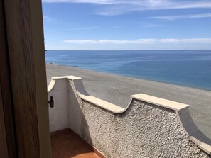 A balcony with a view of a beach and the sea.