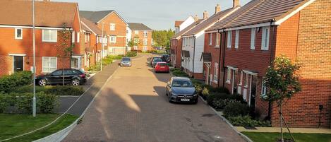 Calle residencial bordeada de casas de ladrillo, con una vía pavimentada y automóviles estacionados.