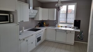 A modern kitchen with white cabinets, a microwave, a sink, and a window with a view of buildings.
