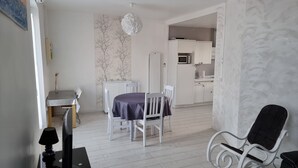 Eine moderne Küche mit weißen Schränken, einer Mikrowelle und einem Essbereich mit Tisch und Stühlen.