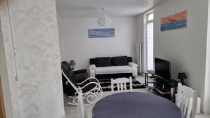 Ein modernes Wohnzimmer mit einer Couch, einem Fernseher und einem Essbereich.
