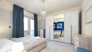 Ein modernes Schlafzimmer mit Bett, Nachttisch, Lampe, Kleiderschrank und Schreibtisch mit Stuhl.