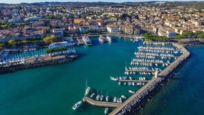Eine Luftaufnahme eines Yachthafens mit zahlreichen angedockten Booten, umgeben von dicht bebauten Stadtgebäuden.