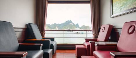 Un balcone con posti a sedere, vista sull'acqua e un quadro appeso al muro.