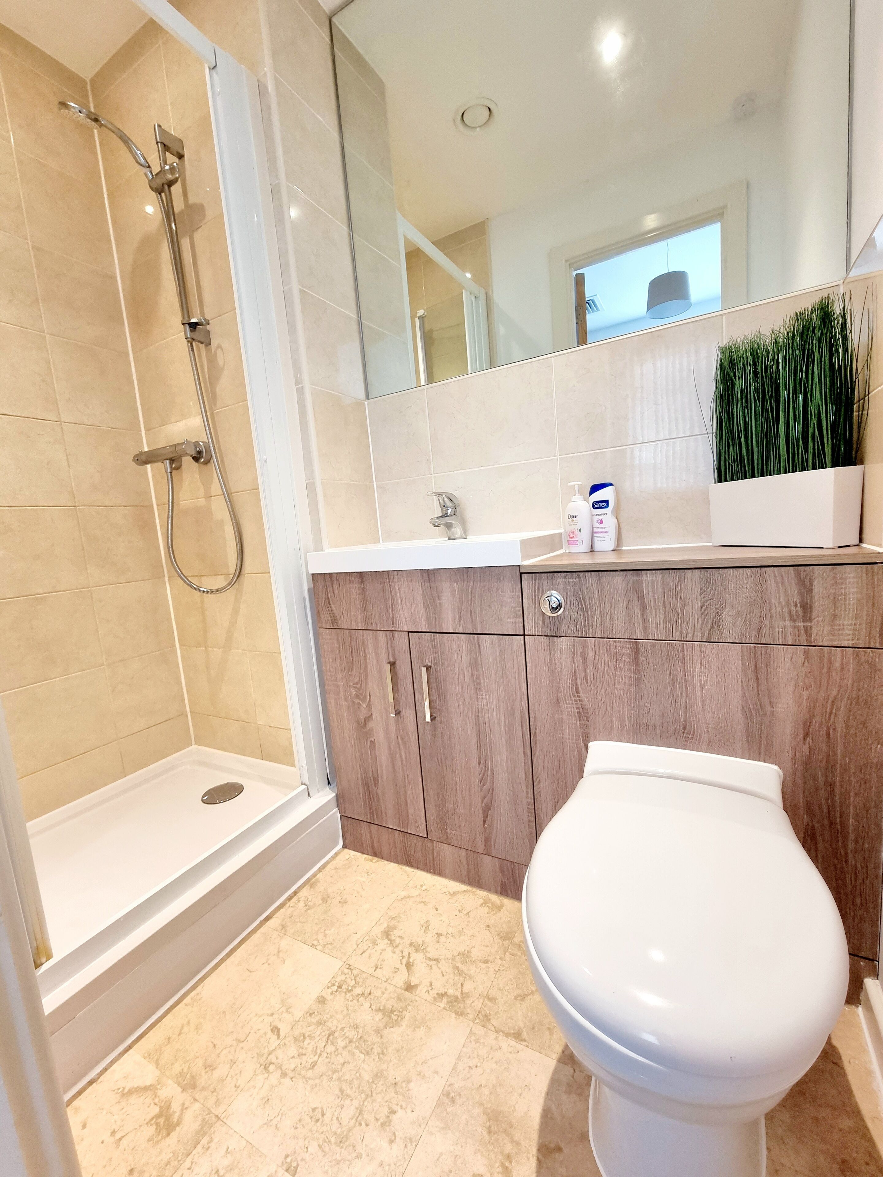 Een moderne badkamer met douche, toilet en wastafel.