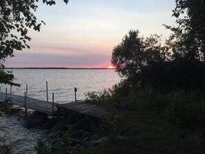Puinen laituri, joka ulottuu tyynen veden ylle, ja taustalla auringonlasku.