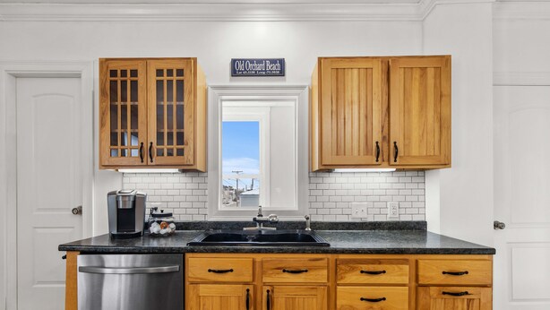 Una cocina con armarios de madera, lavavajillas de acero inoxidable, cafetera y un letrero sobre la puerta.