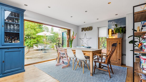 A dining area with a wooden table, chairs, and a blue patterned rug. - Barton Cottage Bed and Breakfast (Dorchester)