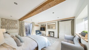 A bedroom with a large bed, a chair, a desk, a fireplace, and a wardrobe. - Barton Cottage Bed and Breakfast (Dorchester)