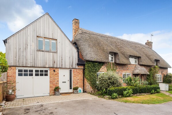 Une maison à deux étages avec une extension en bois et un toit de chaume.