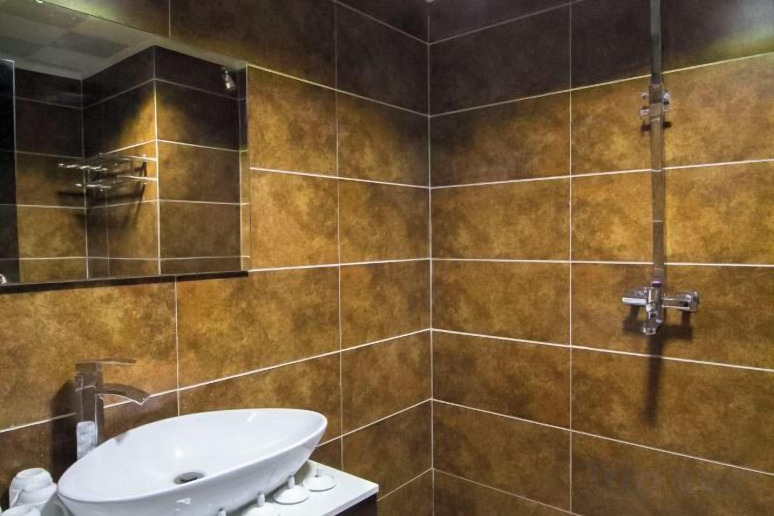 Un bagno con un lavandino bianco, uno specchio e una doccia con un rubinetto cromato.