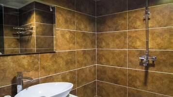 Un bagno con un lavandino bianco, uno specchio e una doccia con un rubinetto cromato.