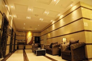 A hotel lobby with a reception desk, leather sofas, a coffee table, and a decorative wall.
