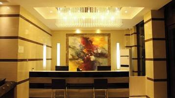 Un'area reception dal design moderno, con una scrivania, due sedie e un grande quadro astratto appeso alla parete.