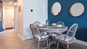 A dining area with a round table, six chairs, and two wall-mounted mirrors. - Beach1 Waterfront Stunning Views (Wasaga Beach)