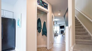 A hallway with a refrigerator, a door with a towel rack, and a staircase. - Beach1 Waterfront Stunning Views (Wasaga Beach)