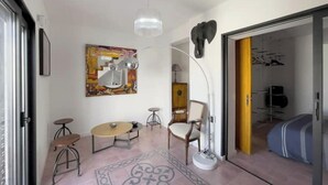 Un soggiorno moderno con un grande quadro astratto, un tavolino rotondo, un divano e una lampada da terra.