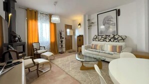 Un soggiorno moderno con divano, poltrone, tavolino in vetro e televisione.