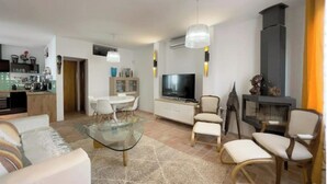 Un soggiorno moderno con un tavolino in vetro, divani bianchi e una TV.