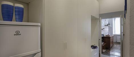 Un pasillo con un refrigerador blanco, un armario blanco y un mueble de madera.