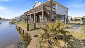 A waterfront house with a covered deck and a dock extending into the water.