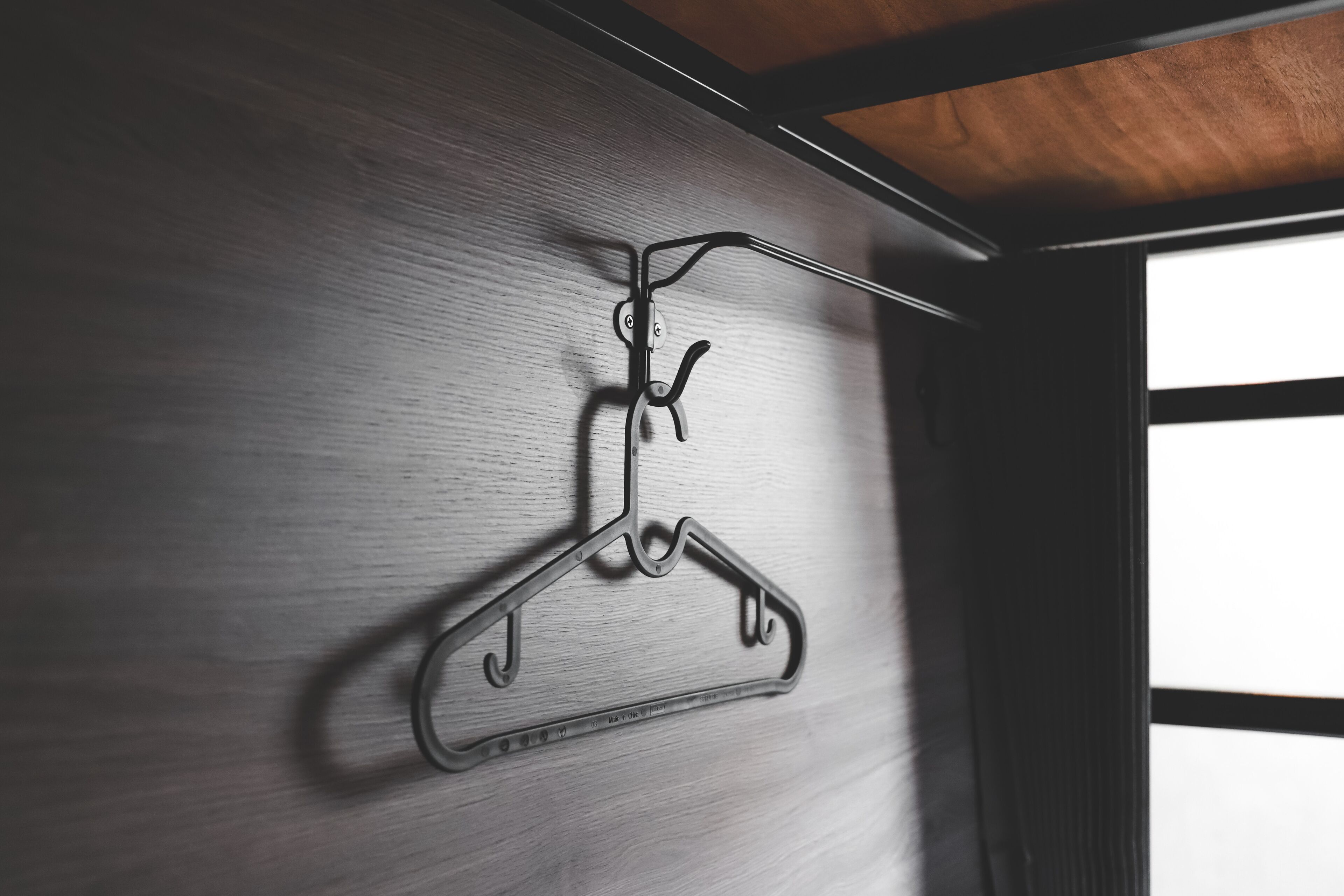 A metal hanger on a wooden wall.