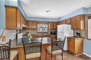 Una cocina con armarios de madera, encimera de granito, refrigerador blanco y cafetera.