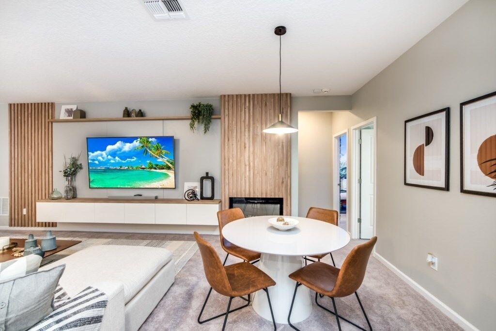Un salon moderne comprenant un téléviseur à écran plat, une table de salle à manger ronde avec des chaises, un canapé et une table basse.