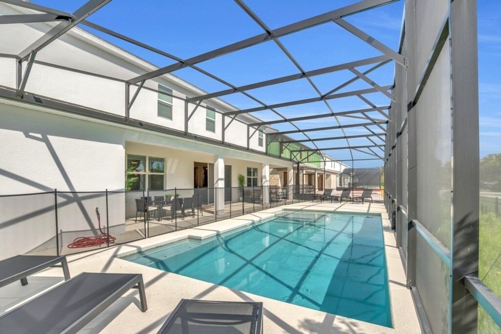 A covered outdoor swimming pool with lounge chairs and a patio area.