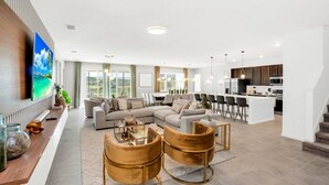 A modern living room with a sofa set, a coffee table, and two armchairs. There is a dining area with a table and chairs, and a kitchen area with a refrigerator and microwave. - The Ultimate New 15 Bedroom Vernada Villa by RedAwning (Kissimmee)