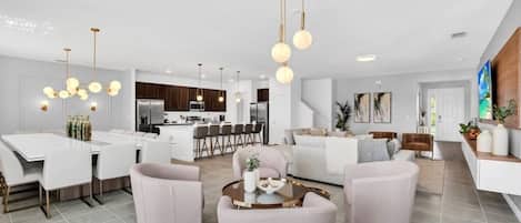 Un salon moderne comprenant un coin repas, une cuisine et un escalier menant à un autre niveau.