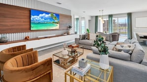 A modern living room with a large flat-screen TV, comfortable seating, and a view of the outdoors. - The Ultimate New 15 Bedroom Vernada Villa by RedAwning (Kissimmee)