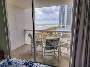 Enjoy the serene beach view from this balcony with a chair and railing.