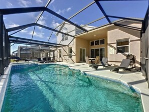 A swimming pool with lounge chairs and a covered patio area. - Luxury 6bd 3.5ba Pool Home In Windsor Palms Resort 6 Bedroom Villa by RedAwning (Kissimmee)