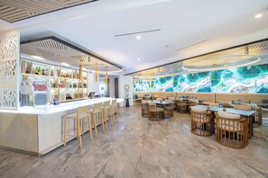 A modern bar area with a counter, seating, and a large decorative wall.