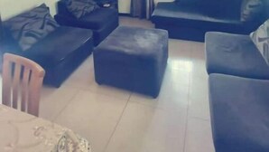 Ein Wohnzimmer mit einer Sofagarnitur, einem Fernseher und einem Fenster mit Vorhängen.