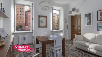 Ein modernes Wohnzimmer mit Essbereich, großen Fenstern und Stadtblick, einem weißen Sofa und einem Holztisch.