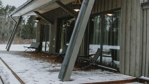 Puinen mökki, jossa on katettu kuisti ja suuret ikkunat.