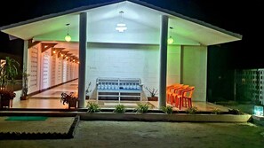 A modern building with a covered entrance, a bench, and potted plants.