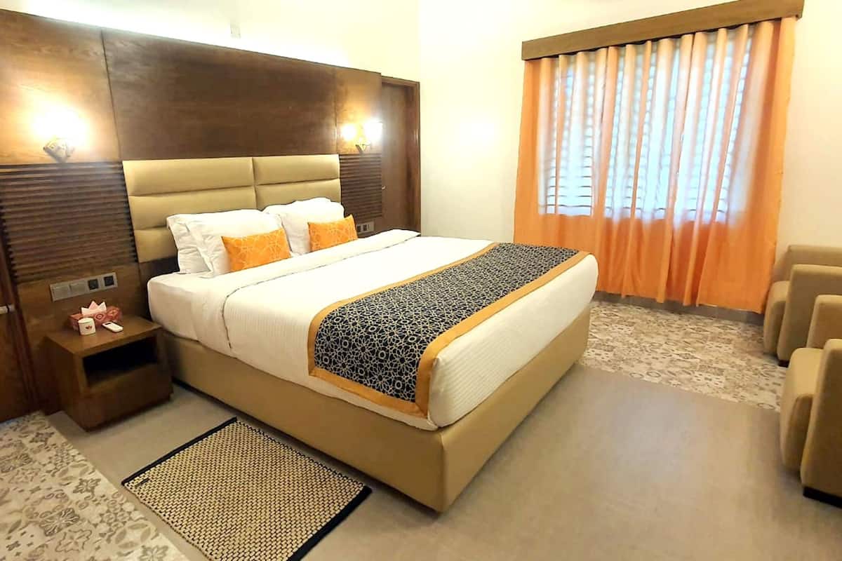 Ein Hotelzimmer mit einem großen Bett, einem Holzschrank, einem Nachttisch, einem Sessel und einem Fenster mit Vorhängen.